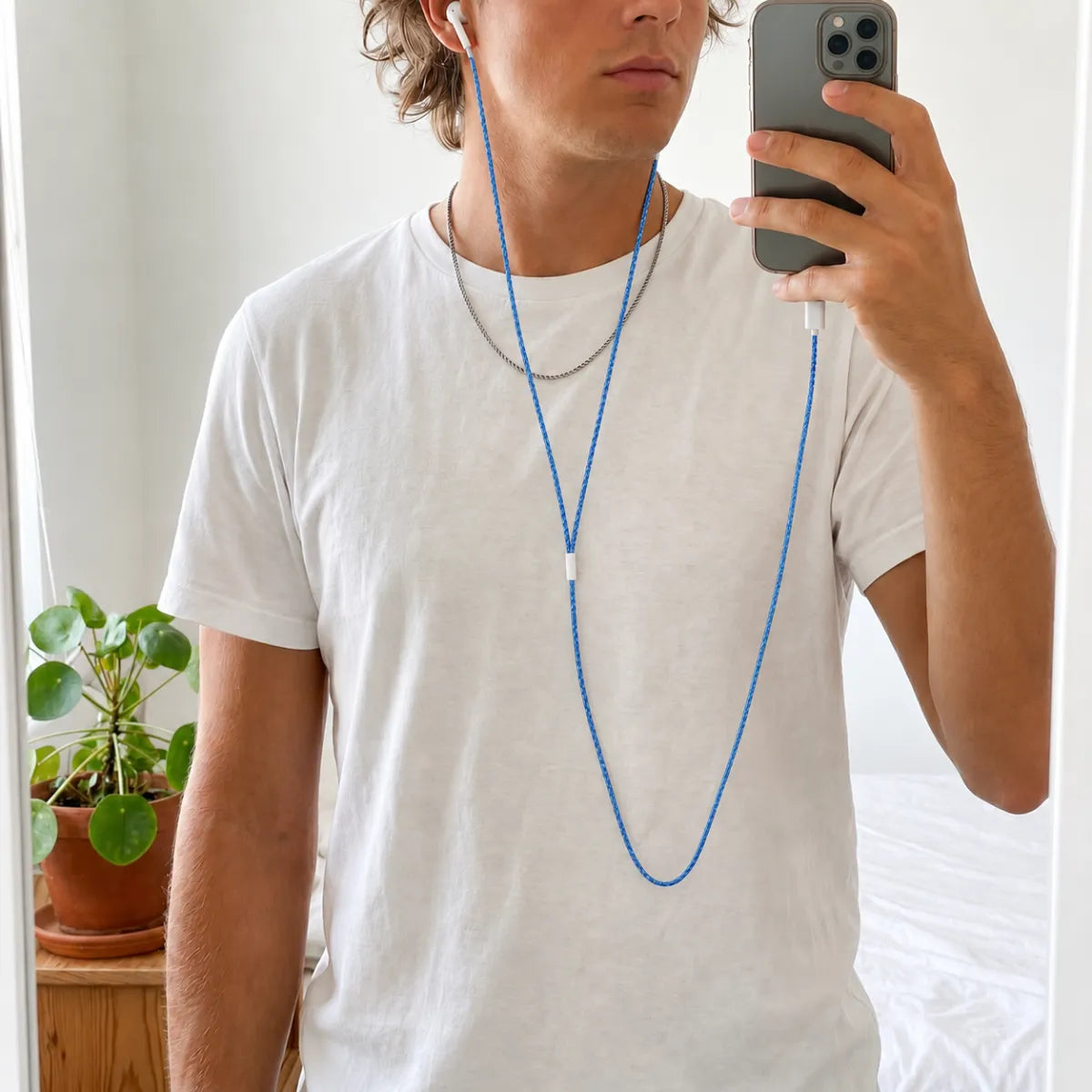 Bedroom mirror selfie of person in a plain white t-shirt and silver chain necklace with deep ocean blue crochet wrapped earphones draped at the neck as a coastal-style cord accessory