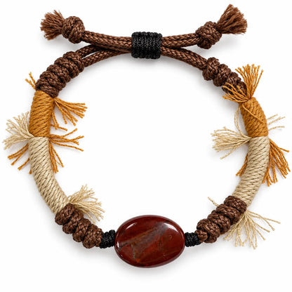 Red jasper bracelet with an oval brick-red stone on brown braided cord with mustard and cream wraps and fringe