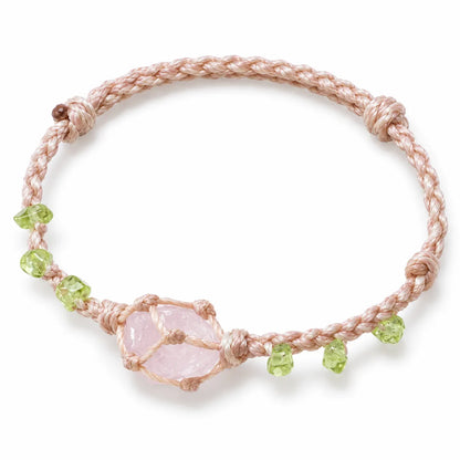 Raw rose quartz bracelet with a natural pink stone in a knotted cord net on blush waxed cord with green peridot chips