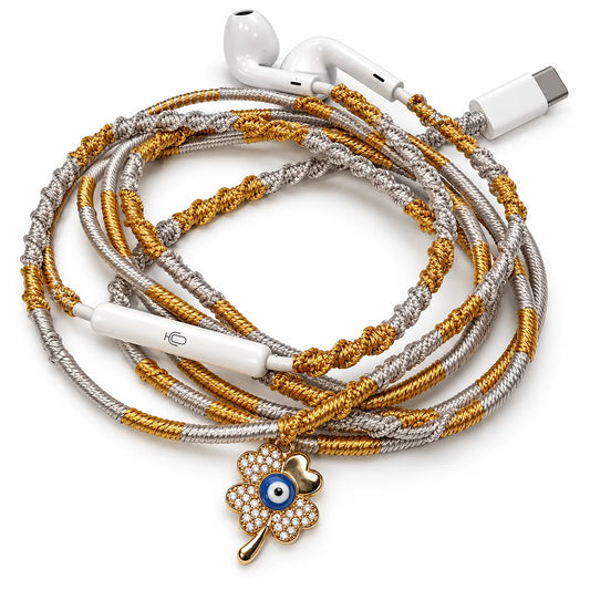 Four-leaf clover evil eye charm on hand-wrapped gold and silver wired earphones with USB-C connector