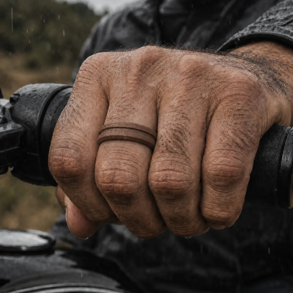 brown silicone ring on middle finger motorcycle handlebar rainy close-up men's waterproof flexible band