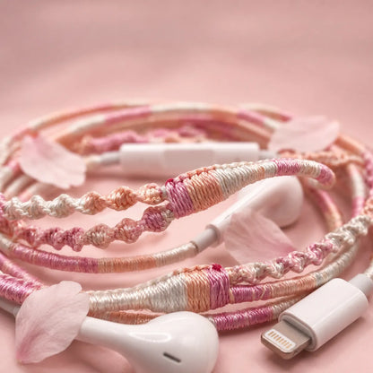 Extreme close-up macro of soft pink peach and cream segmented wrapped earphone cord with scattered cherry blossom petals on a soft blush mist background coquette aesthetic 