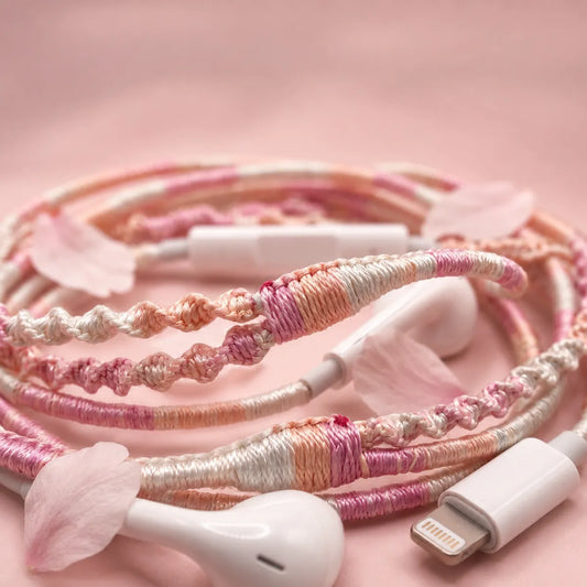  Extreme close-up macro of soft pink peach and cream segmented wrapped earphone cord with scattered cherry blossom petals on a soft blush mist background coquette aesthetic 