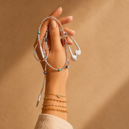 Hand holding an Evil Eye Earphone Wrap featuring metallic gold and silver cord with protective evil eye charms.