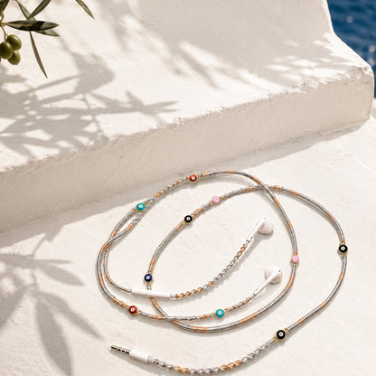 Evil Eye Earphone Wrap with gold and silver braided cord and protective charm accents displayed on a clean white surface.
