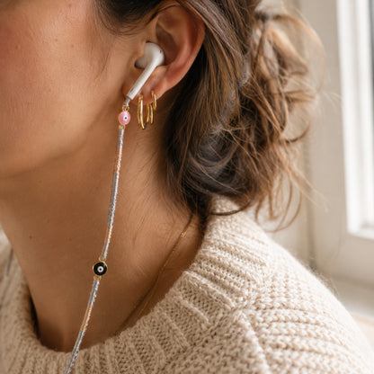 Woman wearing an Evil Eye Earphone Wrap with gold and silver braided cord and protective charm details.
