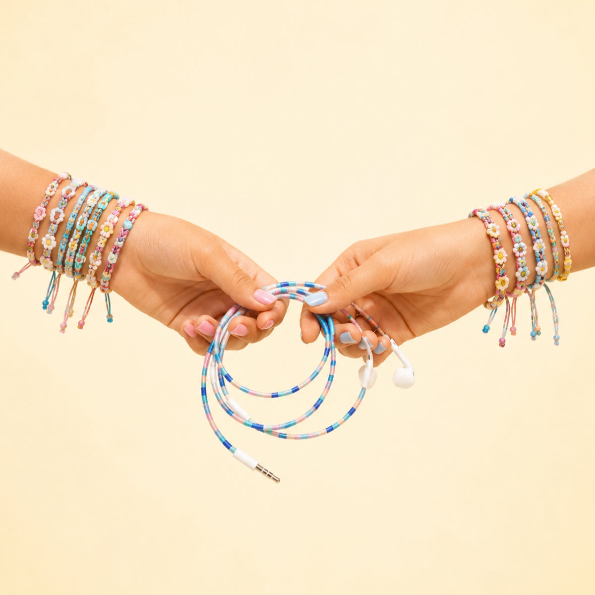 Two hands holding a Friendship Bracelet Earphone Wrap featuring colorful braided cord inspired by friendship bracelet aesthetics.