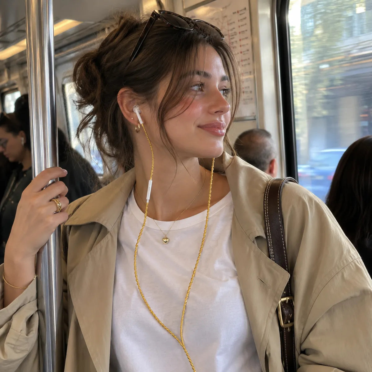  Candid street photography of woman in white t-shirt on subway with gold wrapped earphone cord visible against her white collar, natural daylight commute aesthetic 