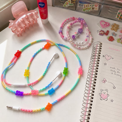 Rainbow Gummy Bear Earphone Wrap arranged on a creative desk surrounded by colorful accessories and stationery.