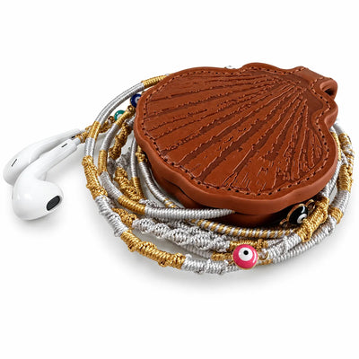 embossed seashell earbuds case with gold and silver braided earphones, close-up