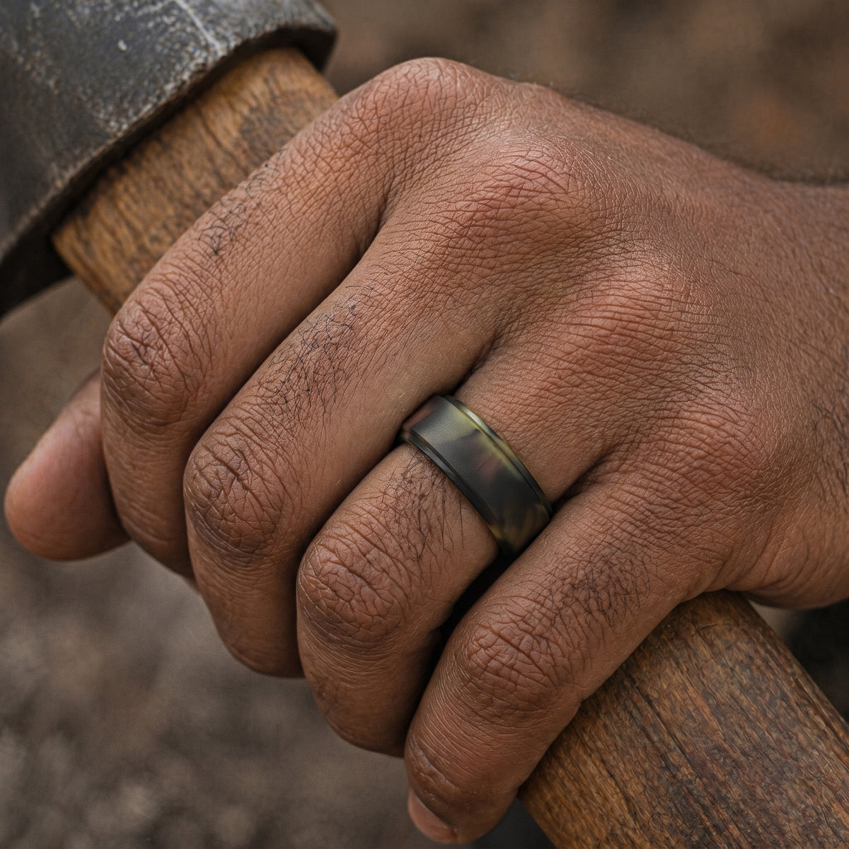 Norelva Woodland Camo polished step edge silicone ring for men worn while gripping a wooden axe handle
