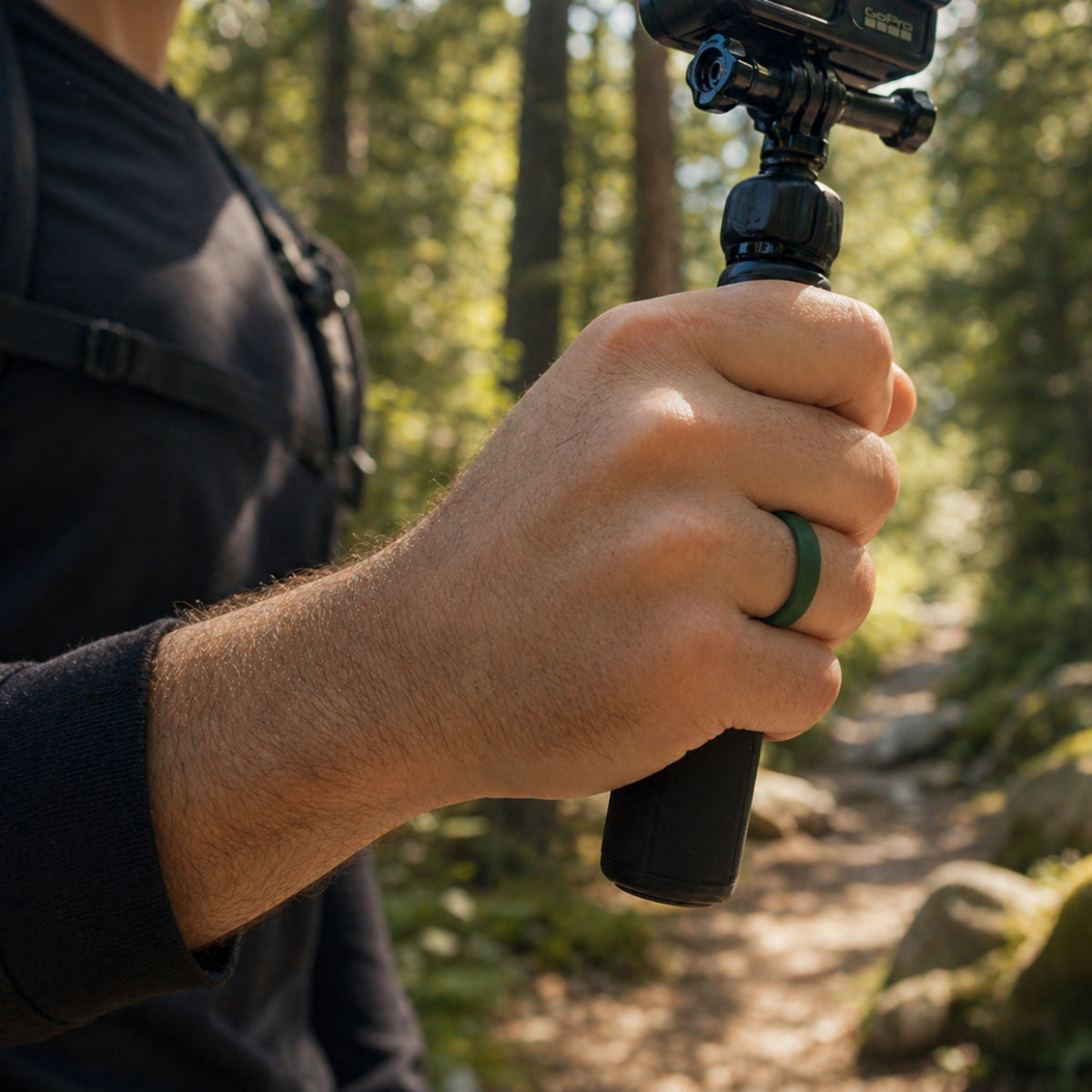 man wearing green silicone ring holding action camera while hiking in forest, durable flexible rubber ring for outdoor adventure