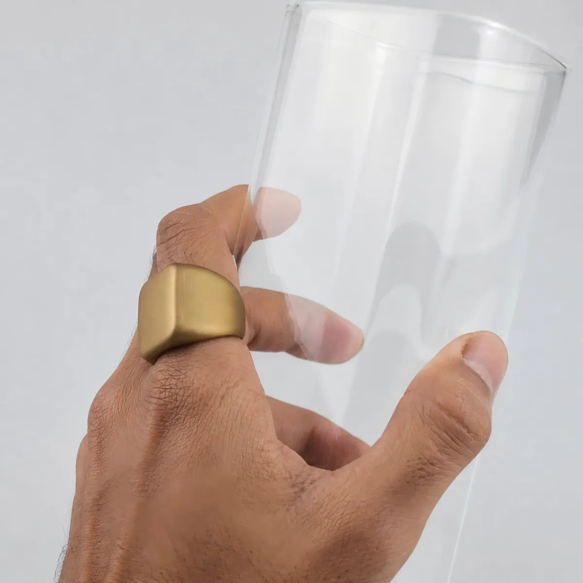 Matallic gold slicone signet ring worn by a man holding a glass