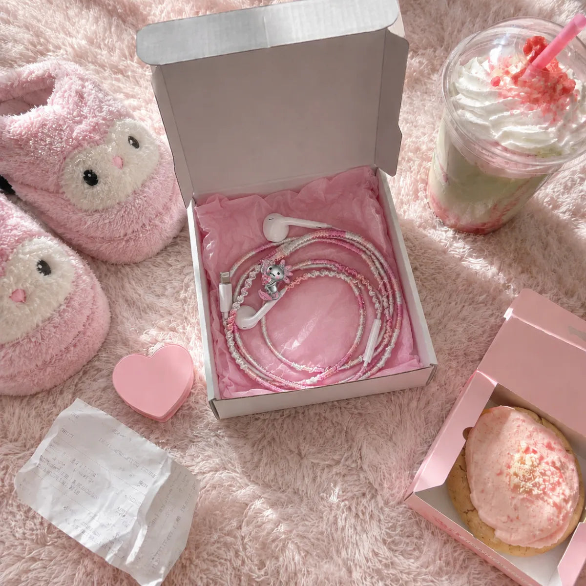  Kawaii pink axolotl earphone wrap unboxed in pink tissue paper on a fuzzy rug with strawberry matcha latte and pink cookie box 