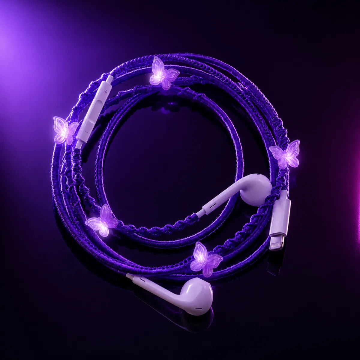  Purple butterfly-charm earphones laid on glossy black surface under violet and magenta gel lighting, high-fashion editorial ad 