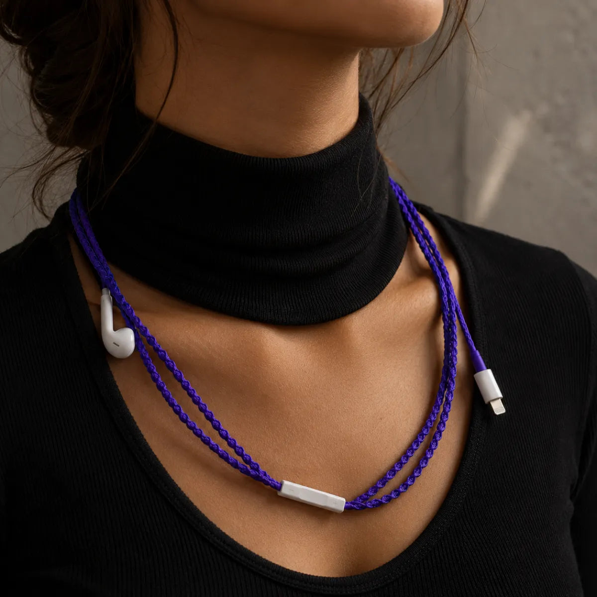  Deep violet earphone wrap worn draped down a woman's neck and collarbone against a black turtleneck, styled like a delicate necklace 